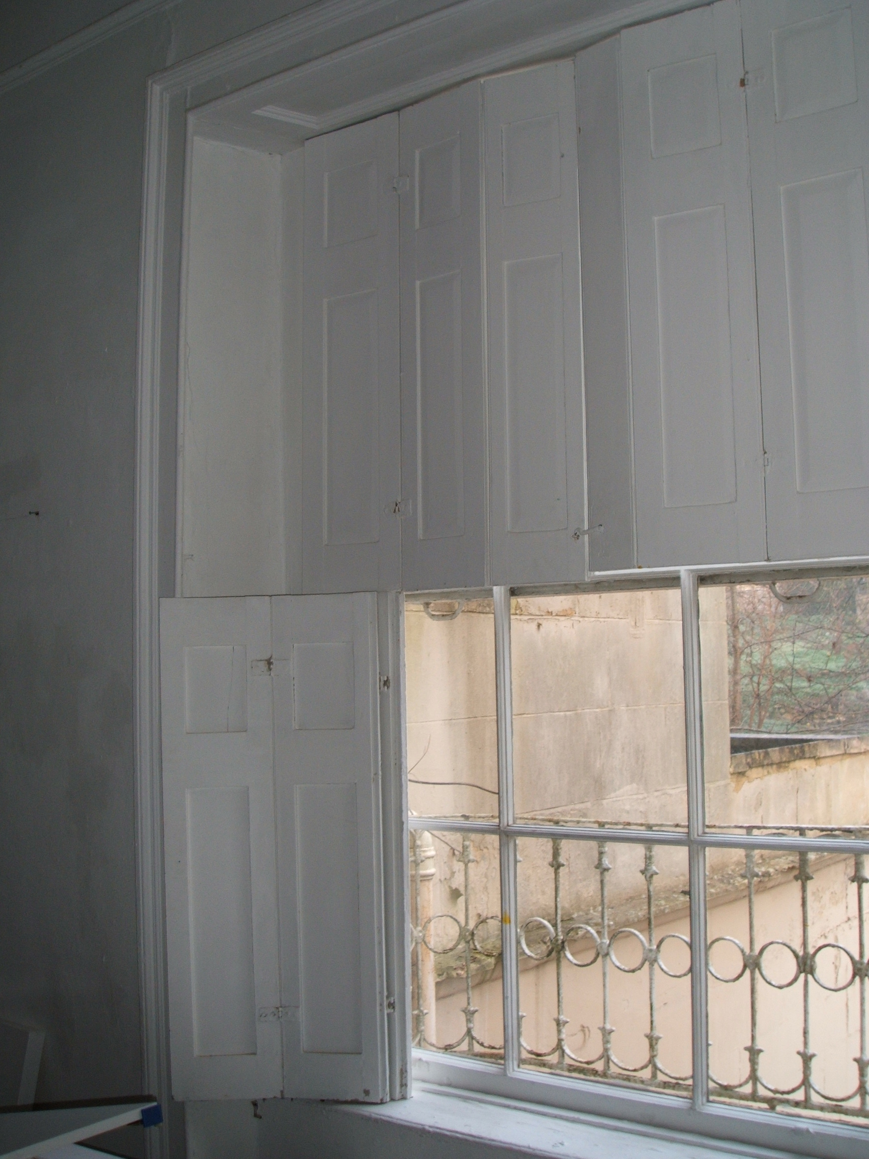 White wooden shutters closed across the top half of a sash window