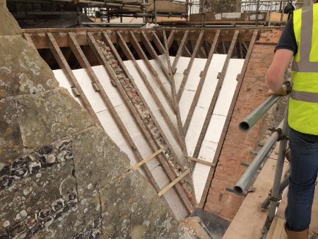 A roof with the rafters exposed and insulation laid between them
