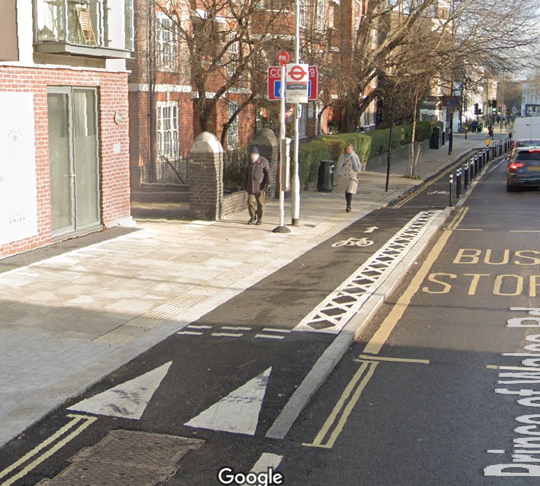 A cycle lane that rises to pavement level and passes in front of a bus stop