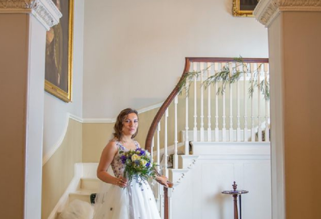 Bride with flowers standing at the bottom of a side staircase